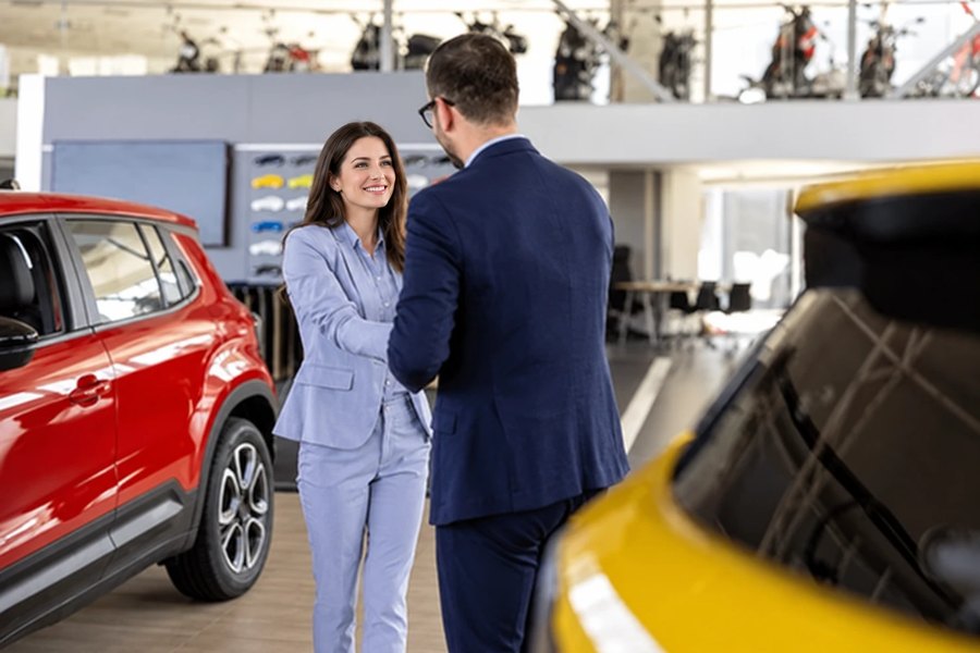Un conseiller serre la main d’une cliente dans un showroom automobile